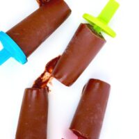 Overhead view of 5 dairy free fudge pops on a white platter ready to be eaten.