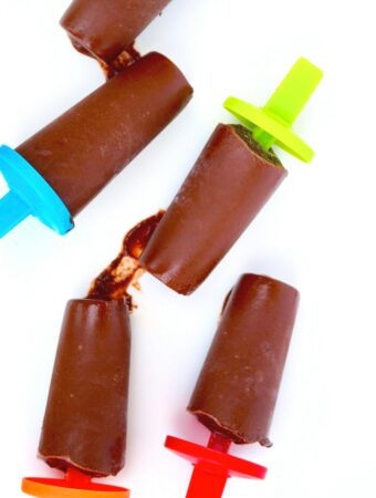 Overhead view of 5 dairy free fudge pops on a white platter ready to be eaten.