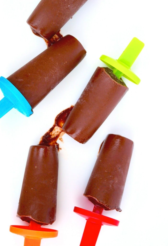 Overhead view of 5 dairy free fudge pops on a white platter ready to be eaten. 