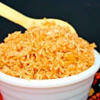 Spanish rice in a white serving bowl with a wooden spoon