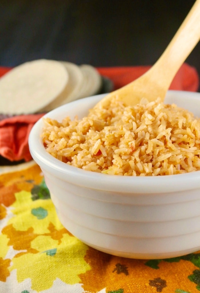 Mexican rice in a white bowl with wooden spoon