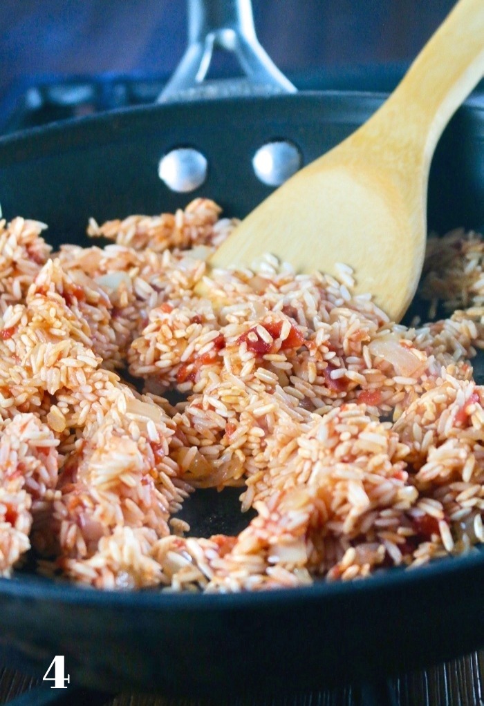 Mixing tomato sauce into rice mix. 