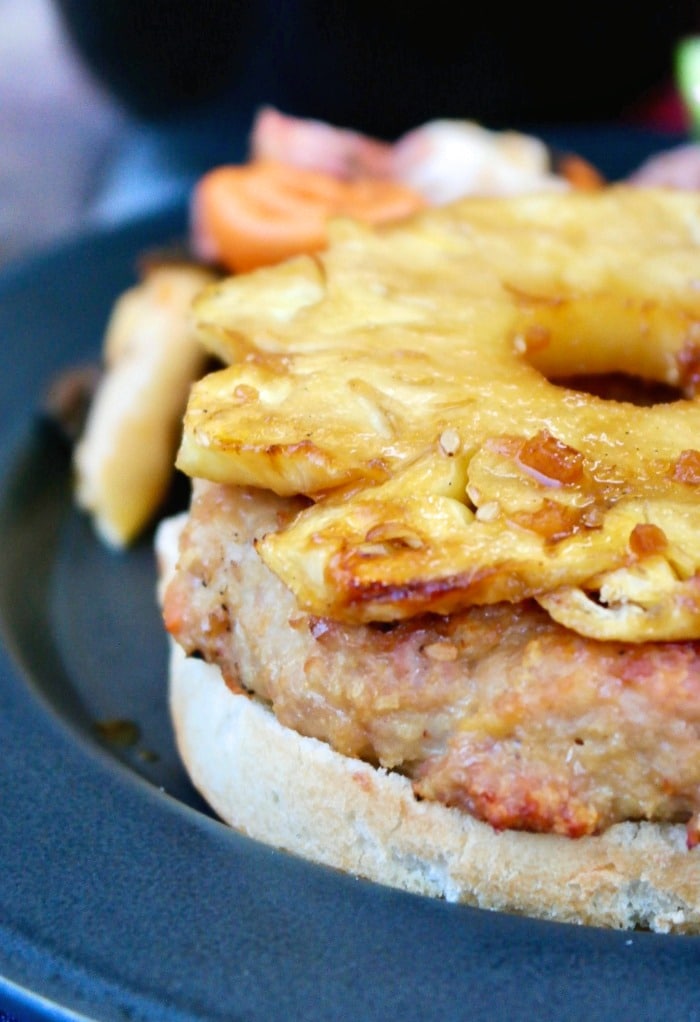 Close up photo of a grilled turkey burger open face topped with pineapple. 