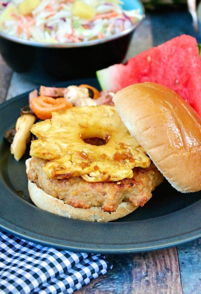 Teriyaki Burger topped with grilled pineapple on a black plate.