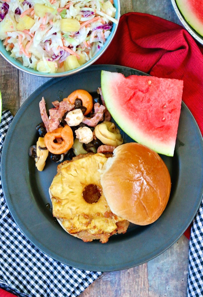 top view of a teriyaki burger with watermelon and coleslaw on the plate. 