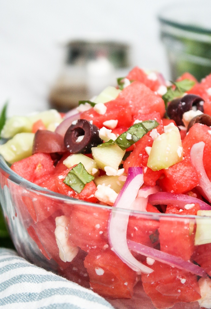 Clear bowl with chopped watermelon, feta and olives. 