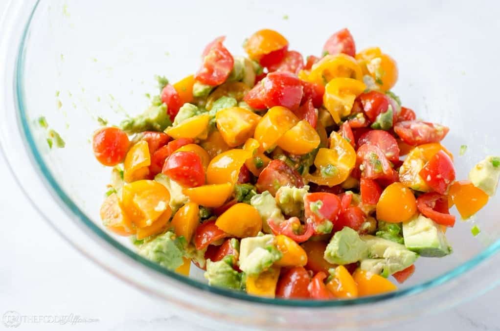 Mixed avocado salsa with tomatoes in a clear bowl for grilled chicken