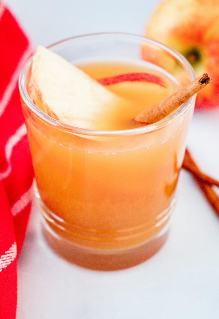 A close up shot of a clear glass filled with apple pie moonshine cocktail. 