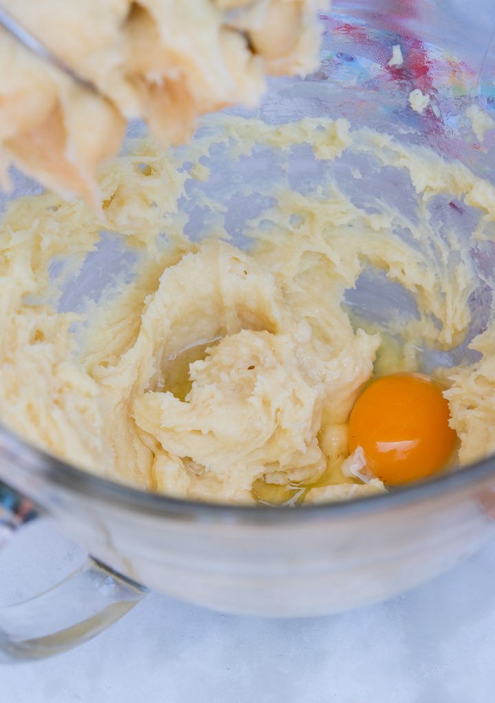 Adding eggs to a pastry dough before blending with a hand mixer.