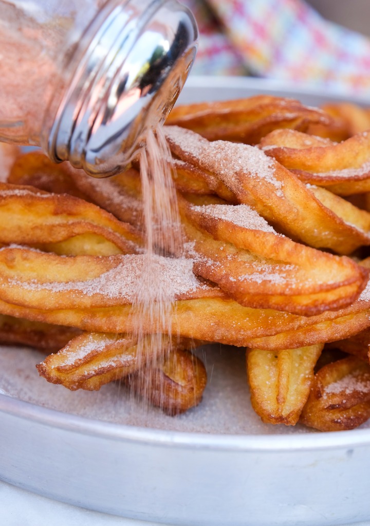 Shaking cinnamon-sugar mix over freshly fried churros. 