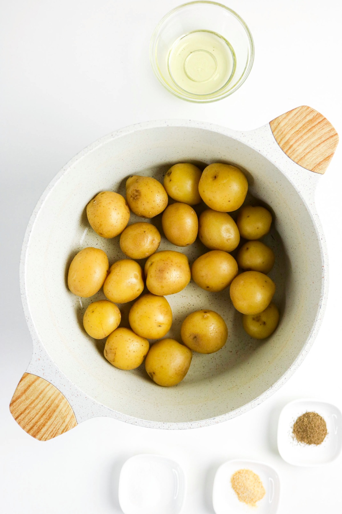 cooked baby potatoes in a large white dutch pan cooling after cooked.