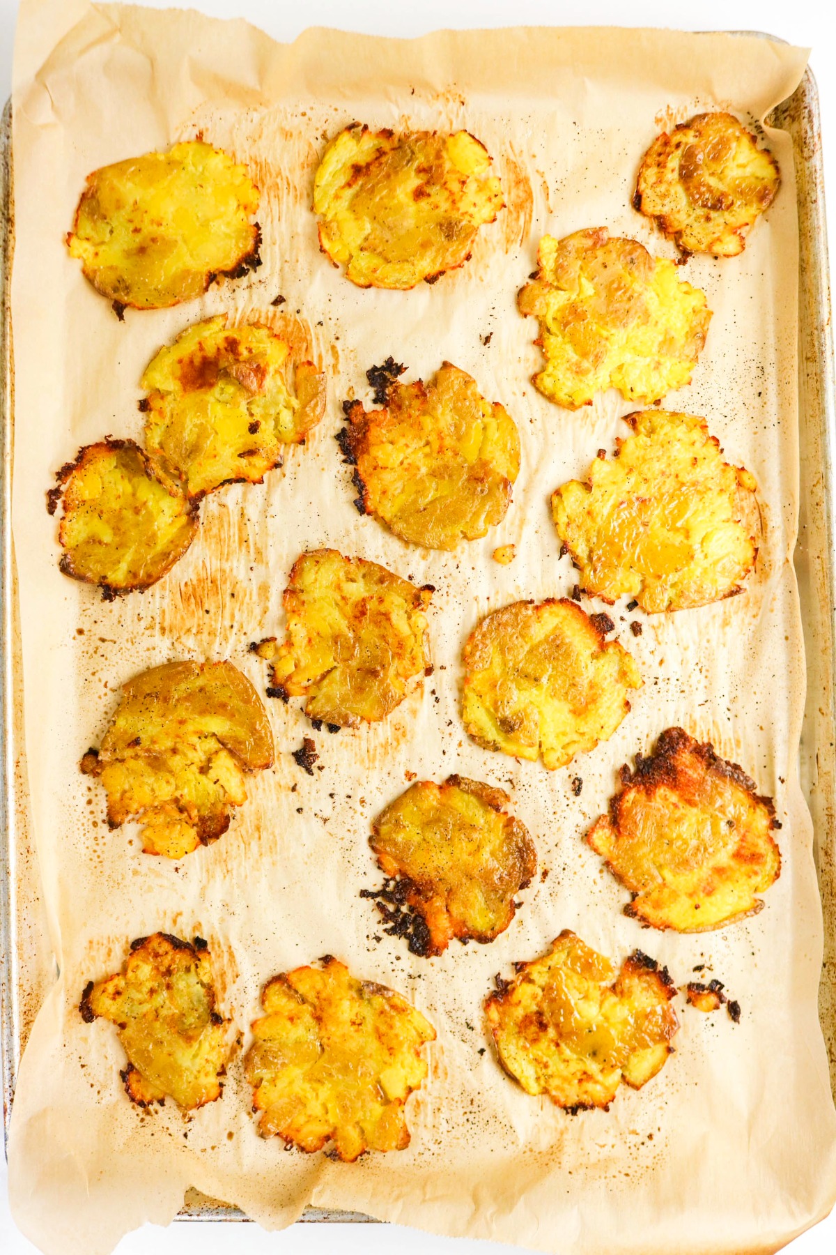 smashed cooked potatoes on a baking sheet lined with parchment paper.