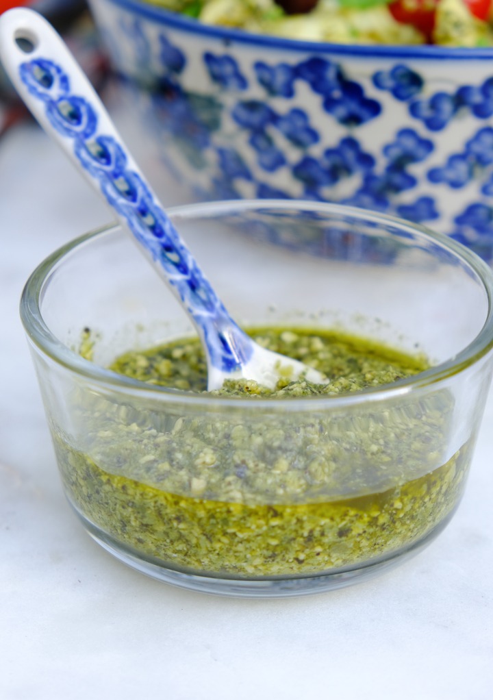 Homemade pesto sauce in a clear small glass bowl. 