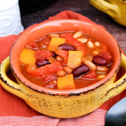 Chili with beans and butternut squash in a yellow soup bowl.