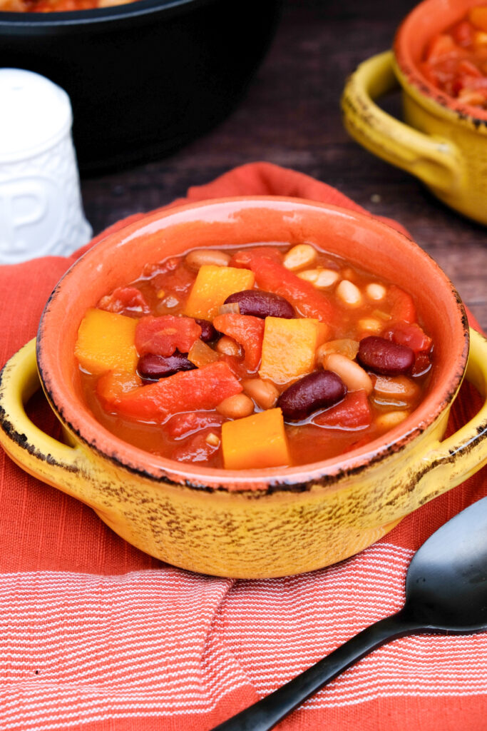 Chili with beans and butternut squash in a yellow soup bowl.