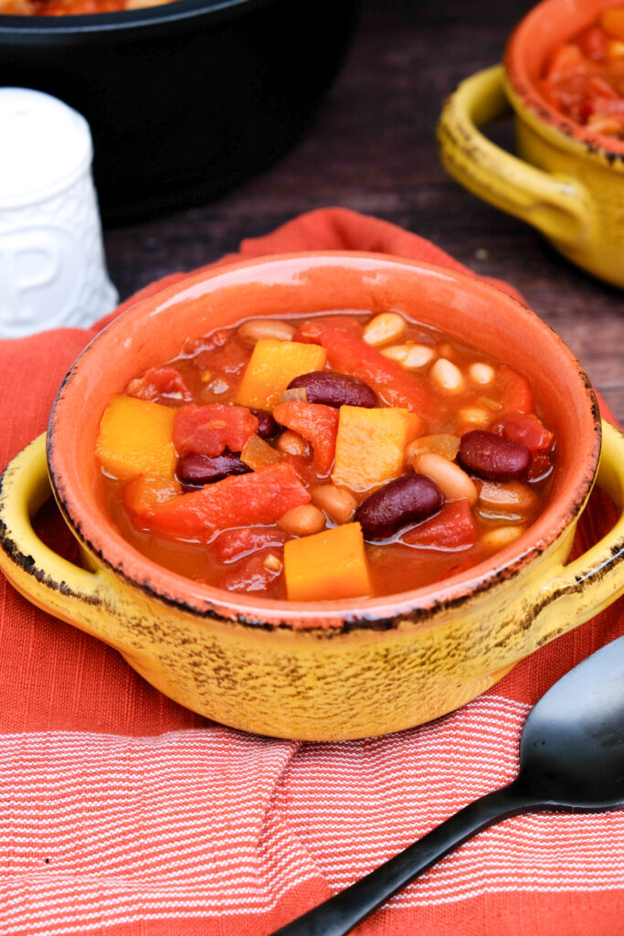 Chili with beans and butternut squash in a yellow soup bowl.