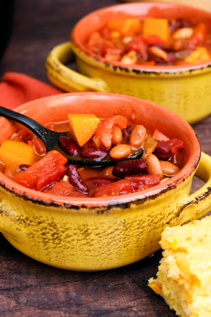 A yellow soup bowl filled with vegetable chili.