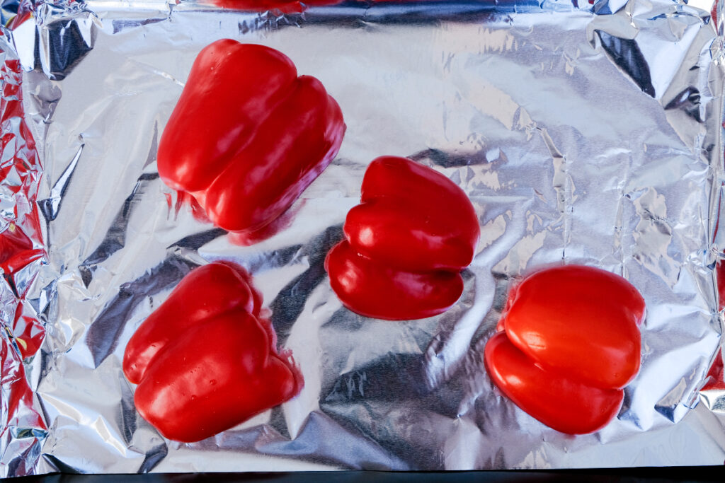Sliced bell peppers on a foil lined baking sheet.
