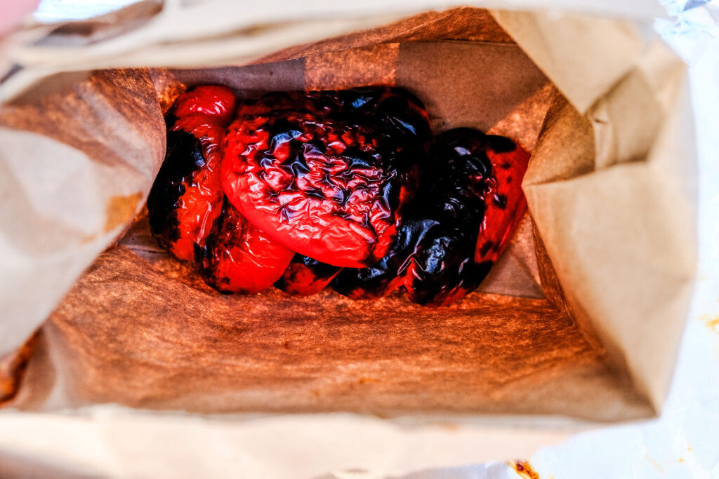 Steaming red bell peppers in a paper bag.