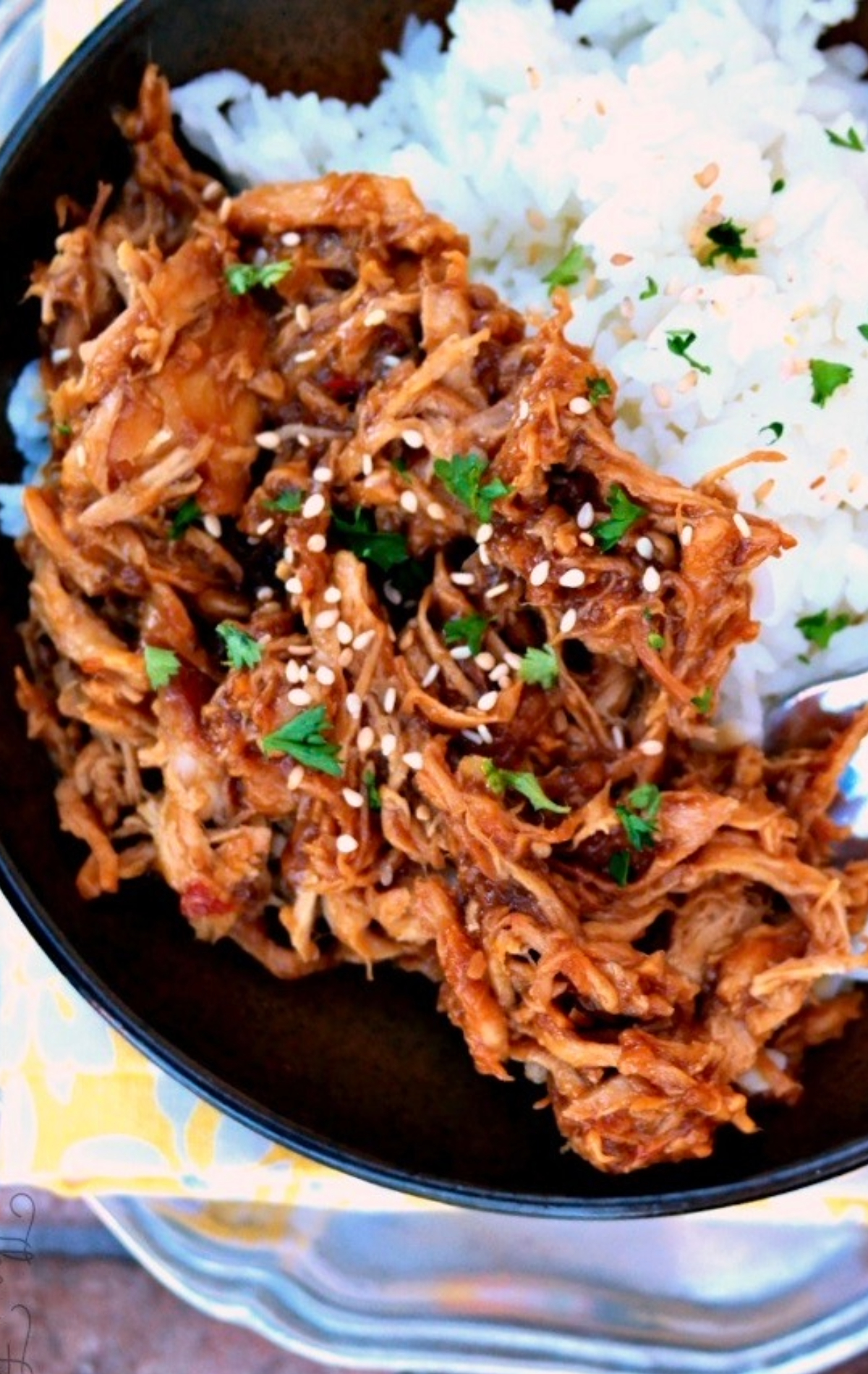 Shredded chicken on a serving plate with chopped green onion. 