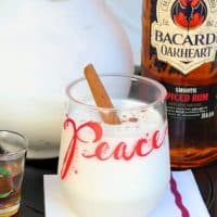 coquito cocktail in a clear glass with the words PEACE with rum on the side