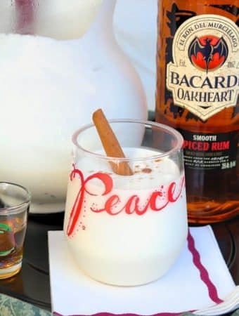 coquito cocktail in a clear glass with the words PEACE with rum on the side