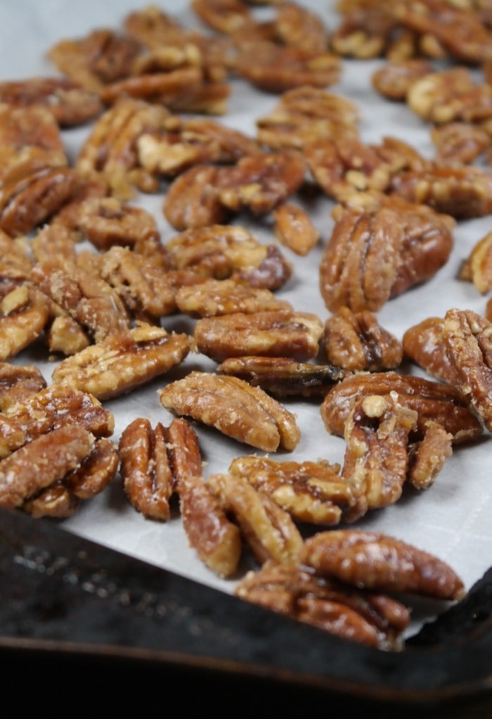 Cooling caramelized pecans on a baking sheet covered with parchment paper. 