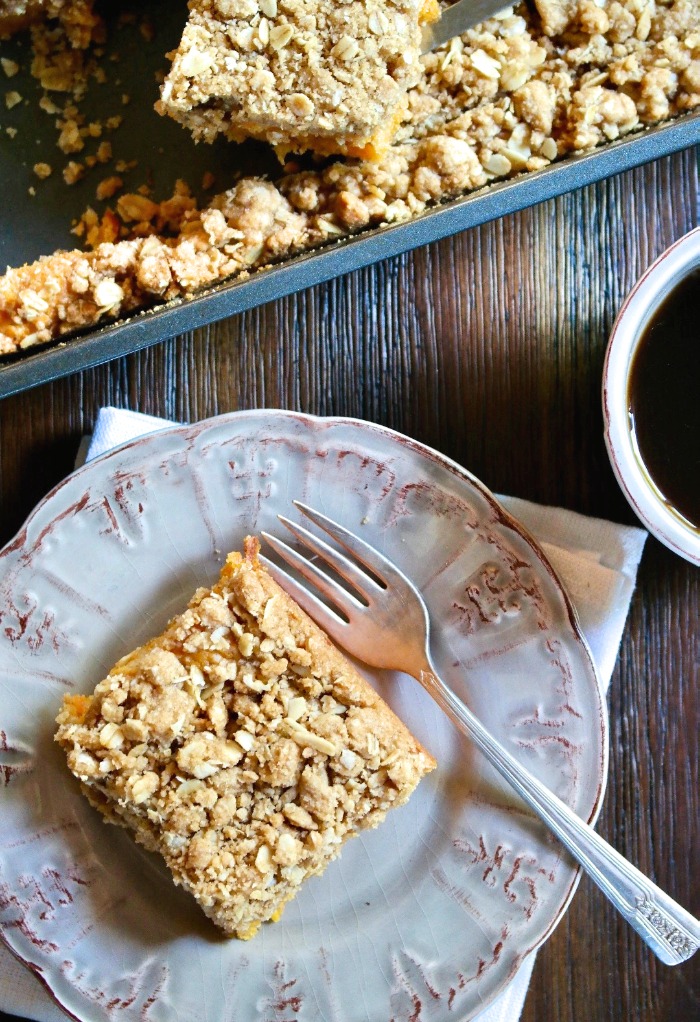 Slice of sweet potato cake on a tan plate with cup of coffee on the side