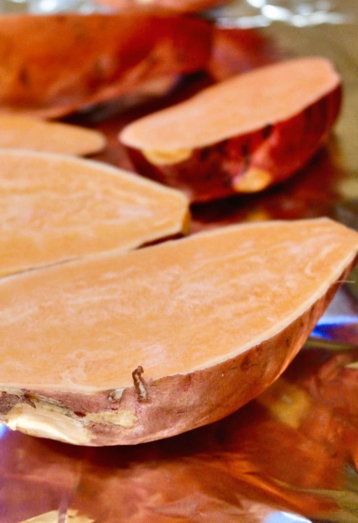 Fresh sweet potatoes sliced on a baking sheet