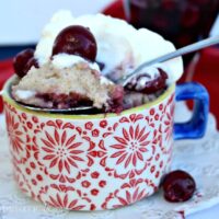 Cherry mug cake in a red cup with blue handle