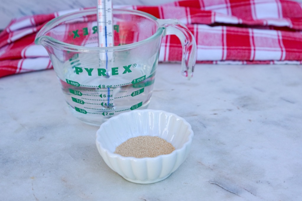 Yeast and warm water in a glass measuring cup.