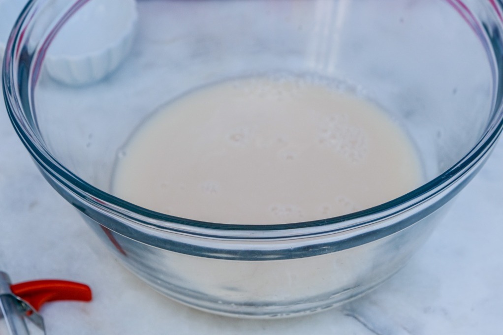 Yeast blooming in water in a clear mixing bowl. 