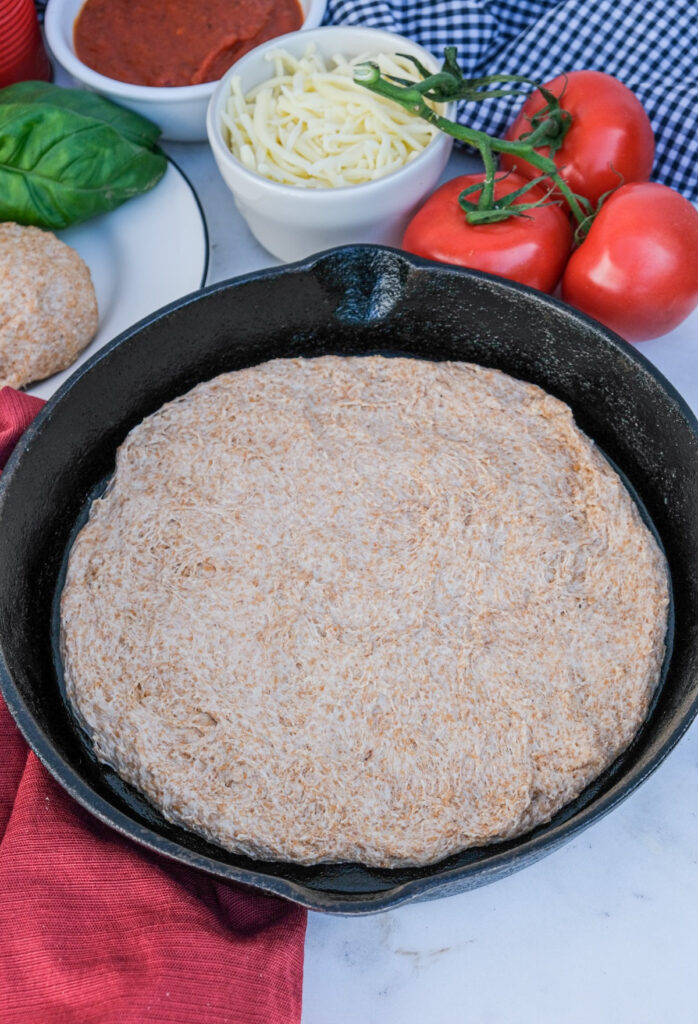 Uncooked pizza dough in a cast iron skillet.