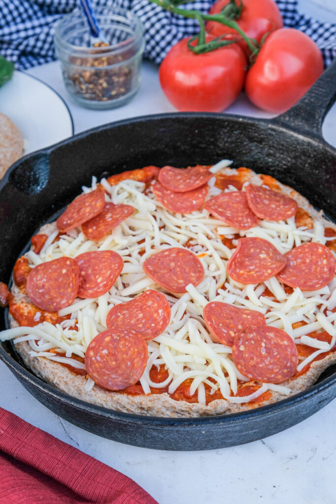 Cheese and pepperoni on a pizza dough before cooking.