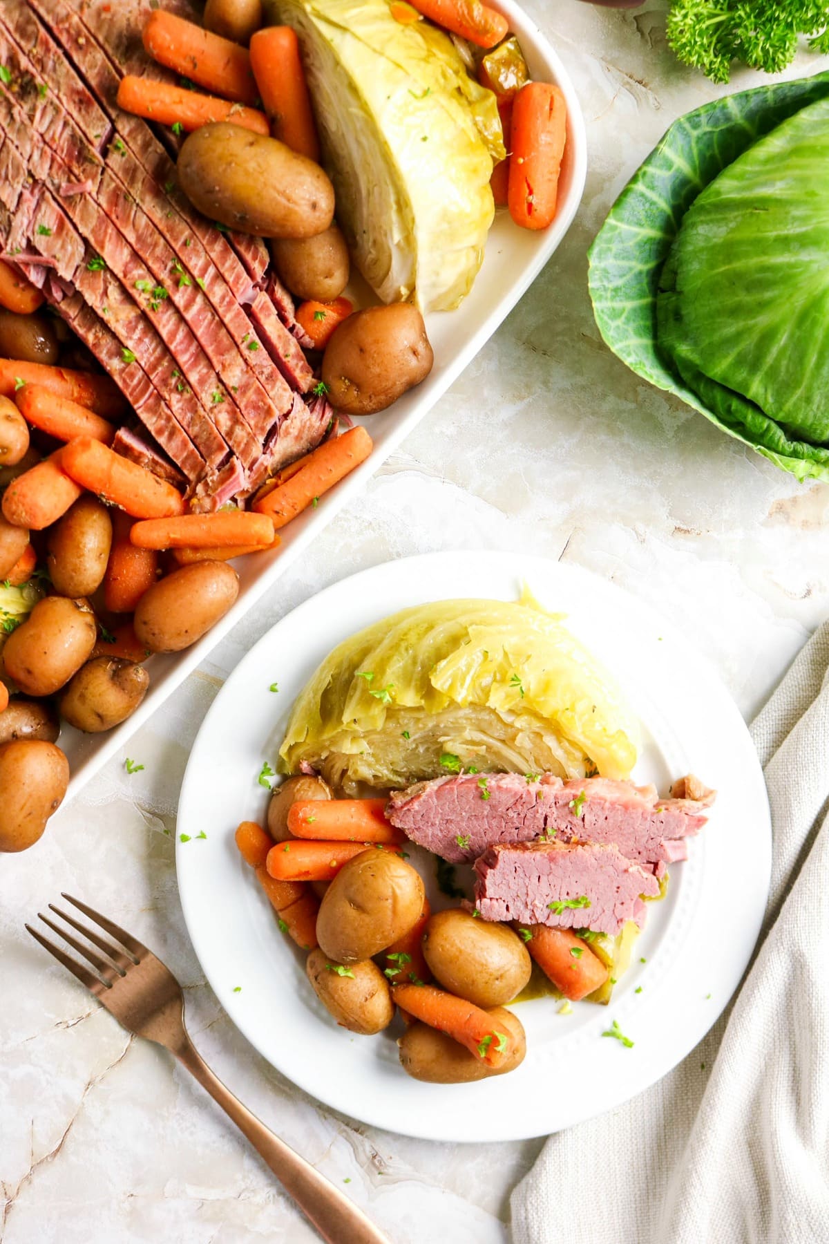 Overhead view of corned beef meal with platter on the side and a dinner plate filled with food.