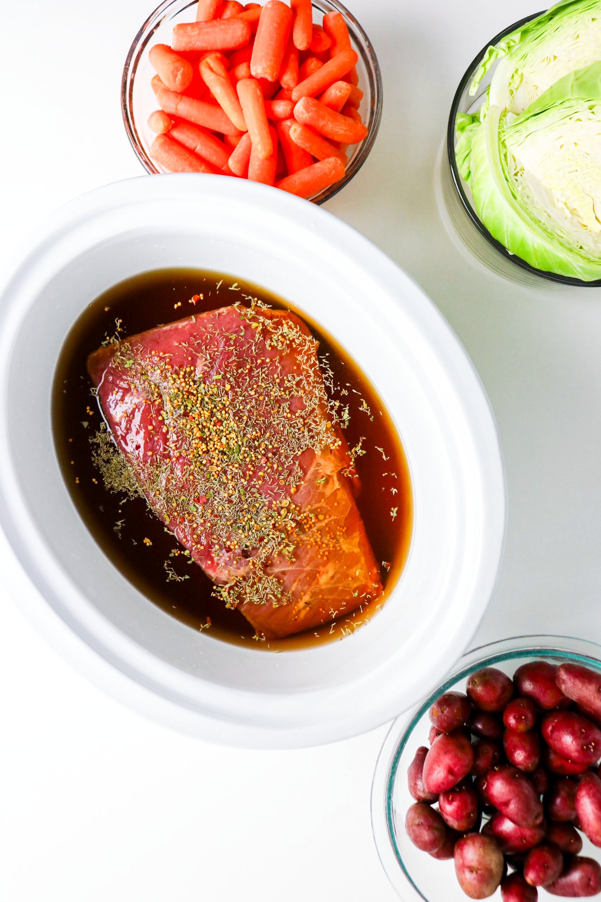 Corned beef with spices in a white slow cooker.