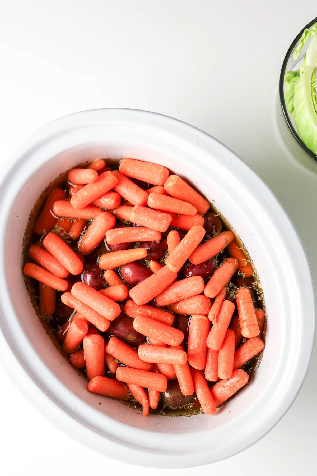 Potatoes and carrots over corned beef in a slow cooker.