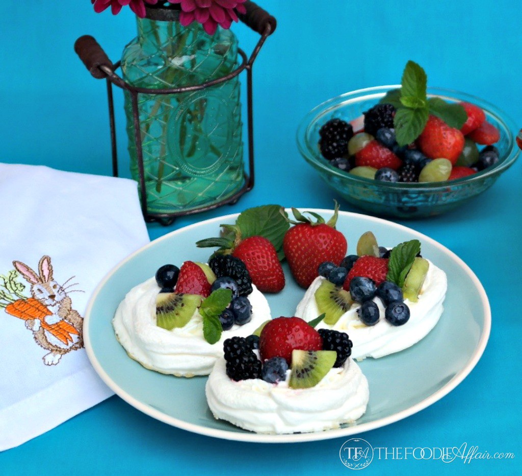 Small individual pavlova nests filled with fruit on a blue plate