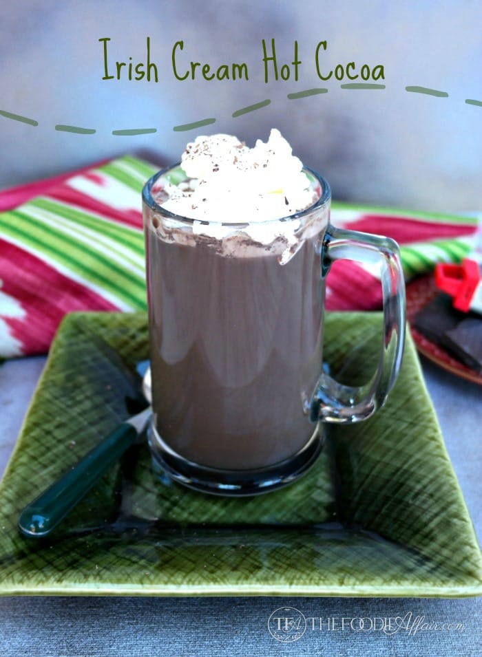 Irish cream hot cocoa in a clear mug on a green plate