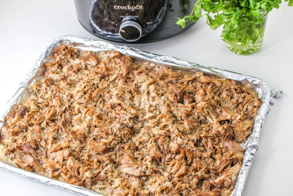 Shredded pork carnitas on a baking sheet. 