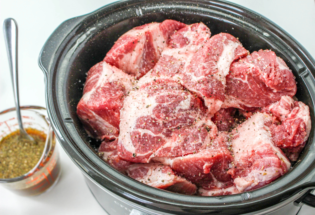 Trimmed pork seasoned and placed in a slow cooker.