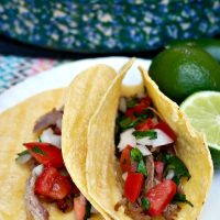 Carnitas wrapped in corn tortillas with pico de gallo