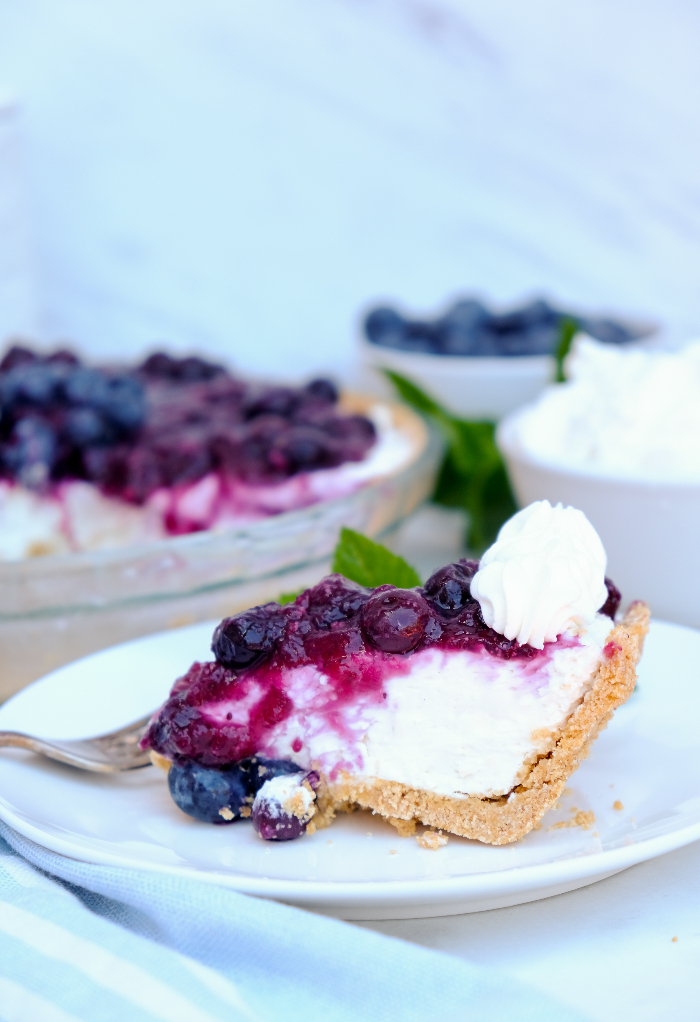 Slice of blueberry cream cheese pie on a white plate.
