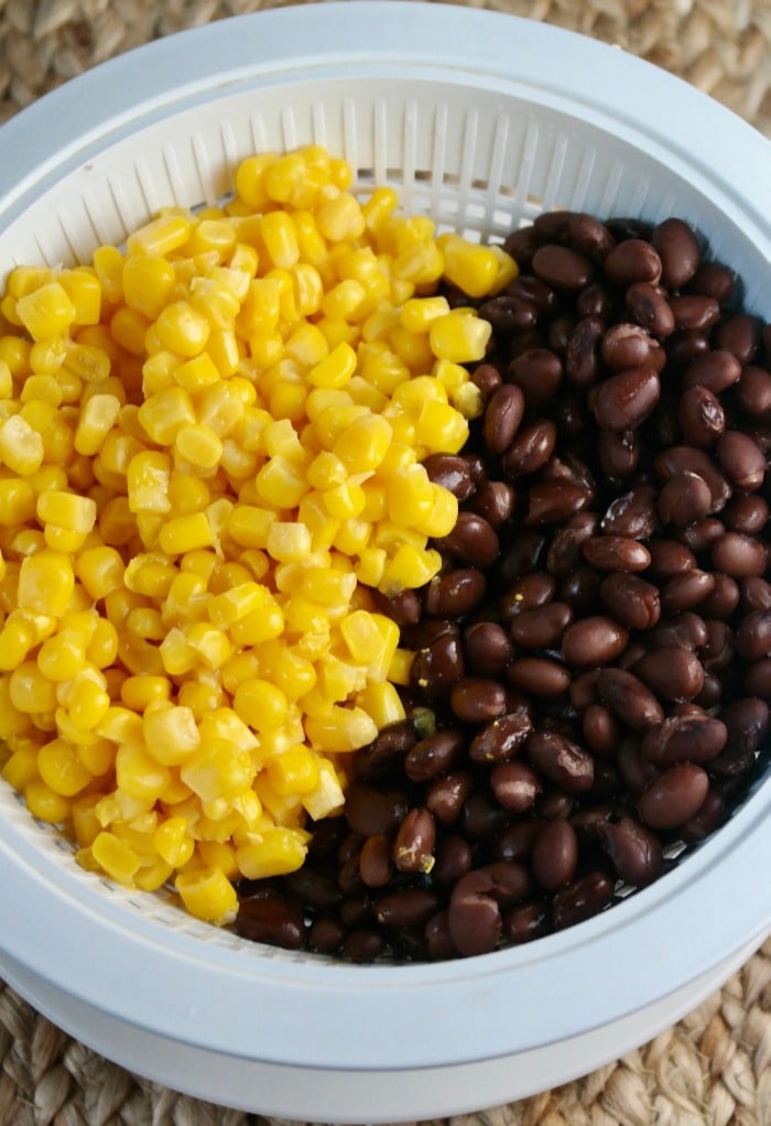 Corn and black beans draining in a white colander 