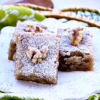 A white place of banana snack bars with a walnut on top of each piece