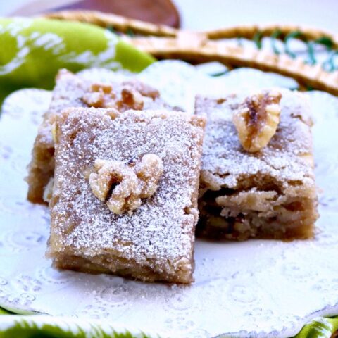 A white place of banana snack bars with a walnut on top of each piece