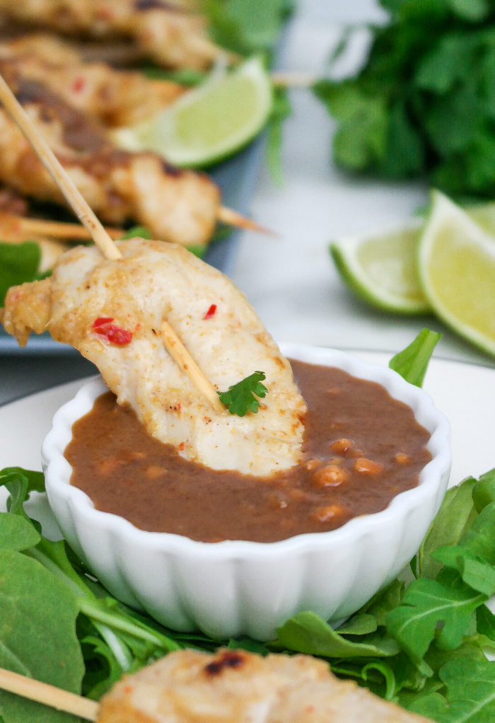  A small bowl of peanut sauce with chicken satay.