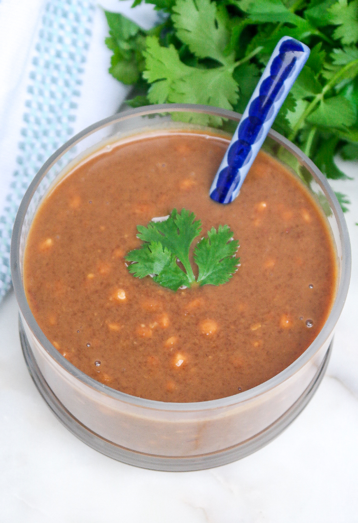 Thai peanut sauce in a clear serving bowl with a ceramic spoon.