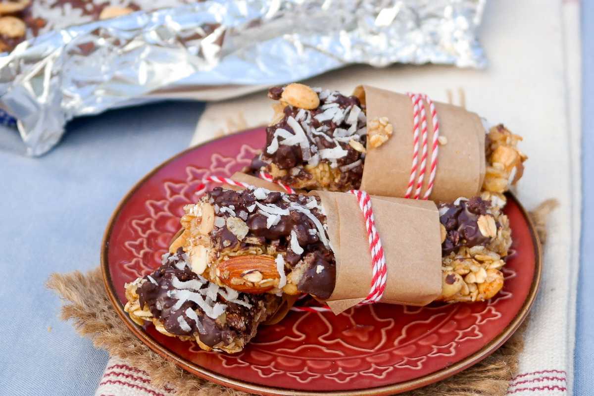 Homemade granola bars on a maroon serving plate wrapped in brown paper. 