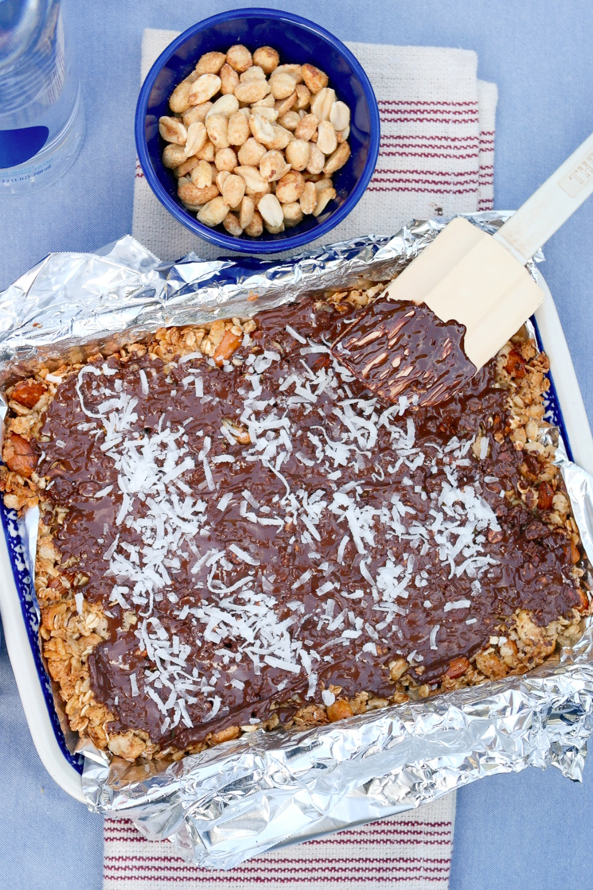 Homemade granola bars topped with chocolate and coconut flakes before cutting. 